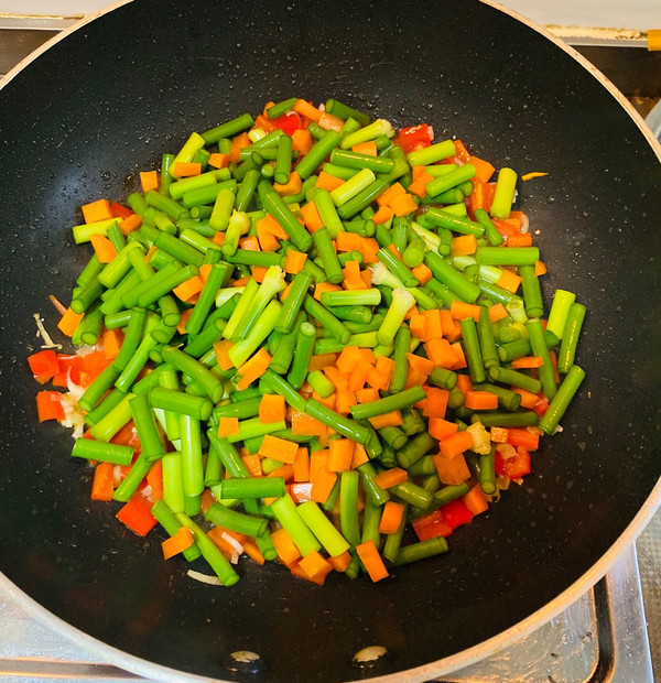 然后加入胡萝卜丁和蒜苔继续翻炒,翻炒均匀加入