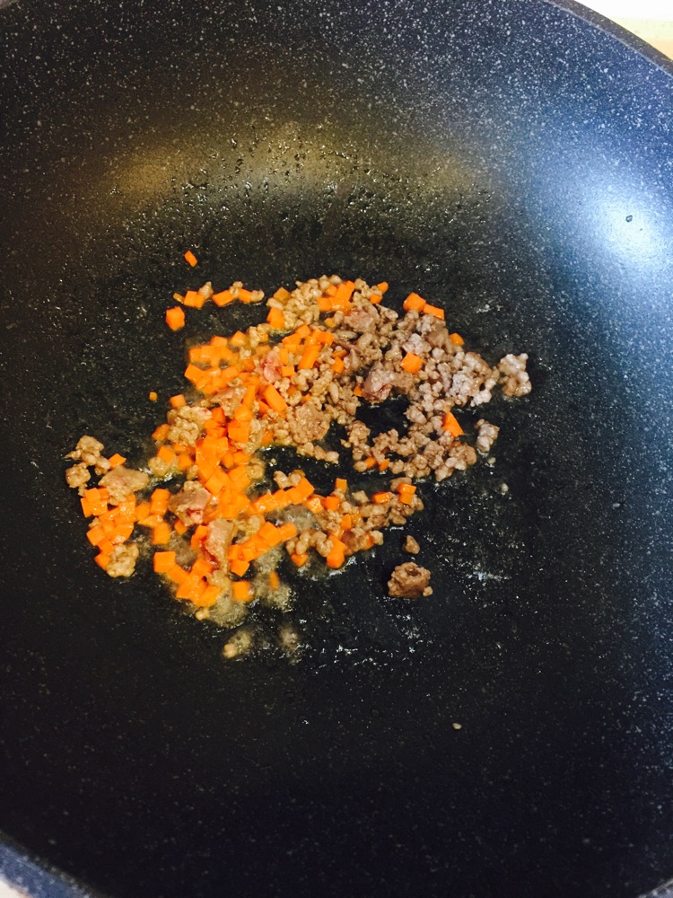 倒入少许油,下牛肉糜和胡萝卜,加少许盐,煸炒