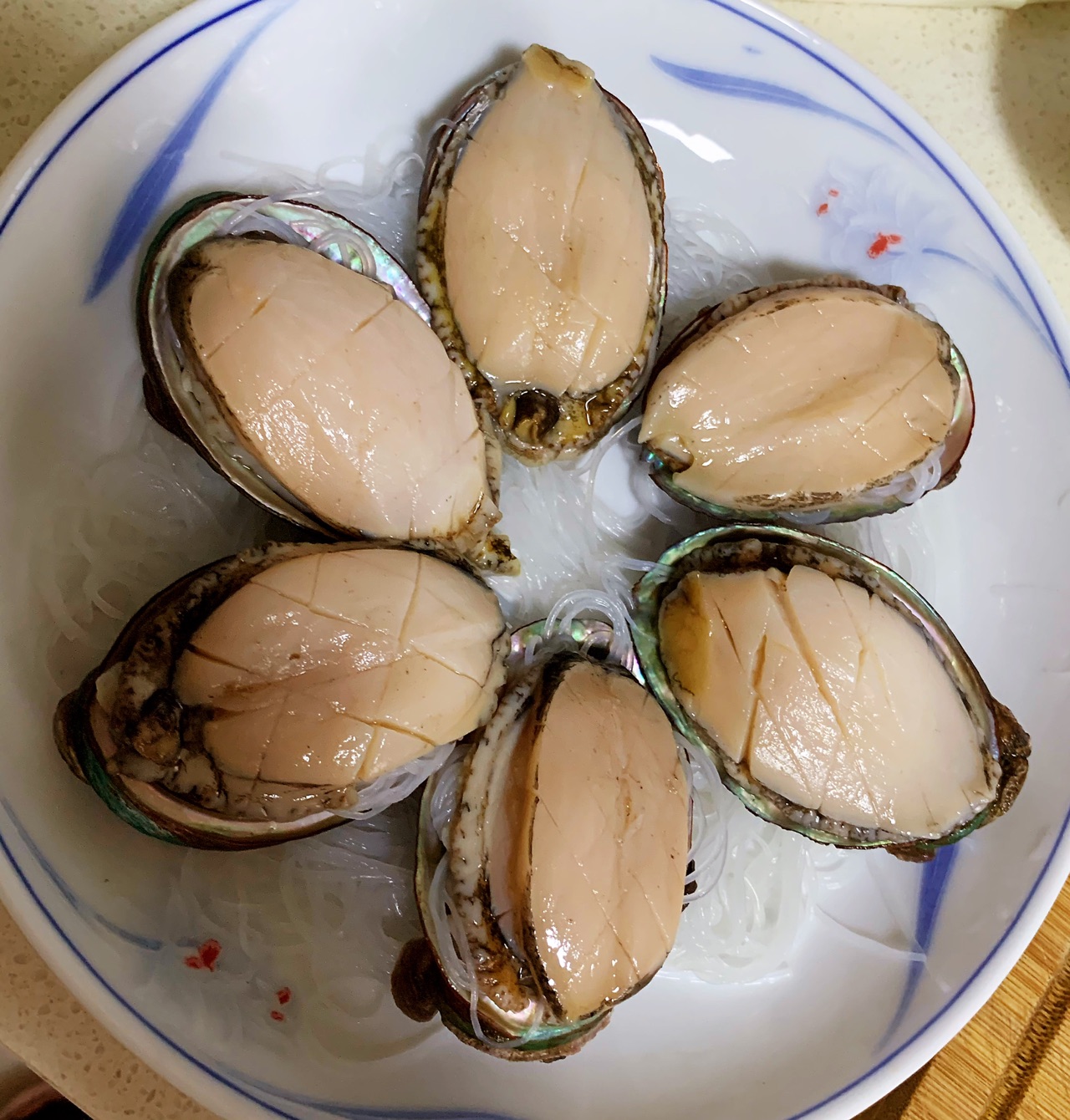在鲍鱼壳里放一点泡好的粉丝,然后放上切片的鲍鱼