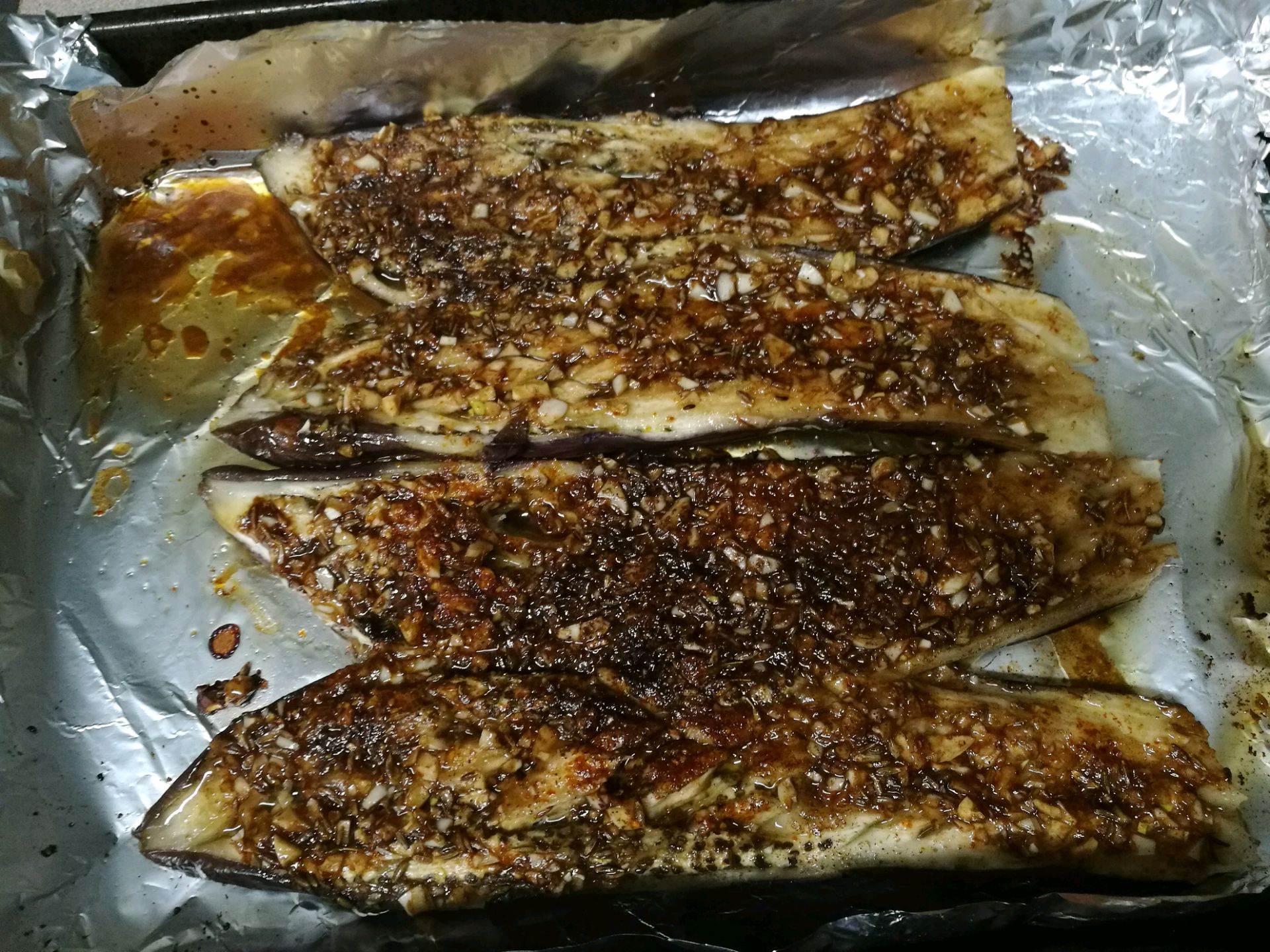 准备好烤盘,并且铺好锡纸. 4. 将蒸好的茄子切开平铺.