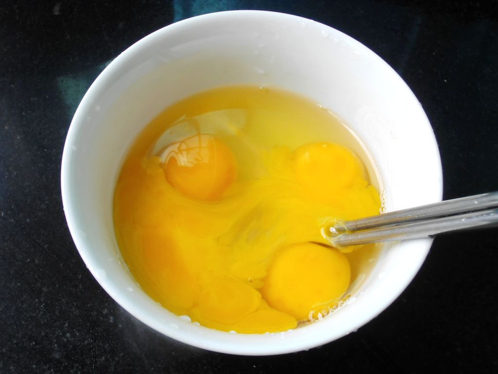 女性双手将鸡蛋打碎在厨房桌子上的陶瓷碗和餐具。照片摄影图片_ID:312561004-Veer图库